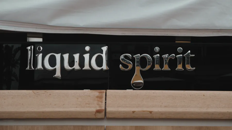 Letras de acero inoxidable pulido con el nombre «liquid spirit» sobre fondo negro